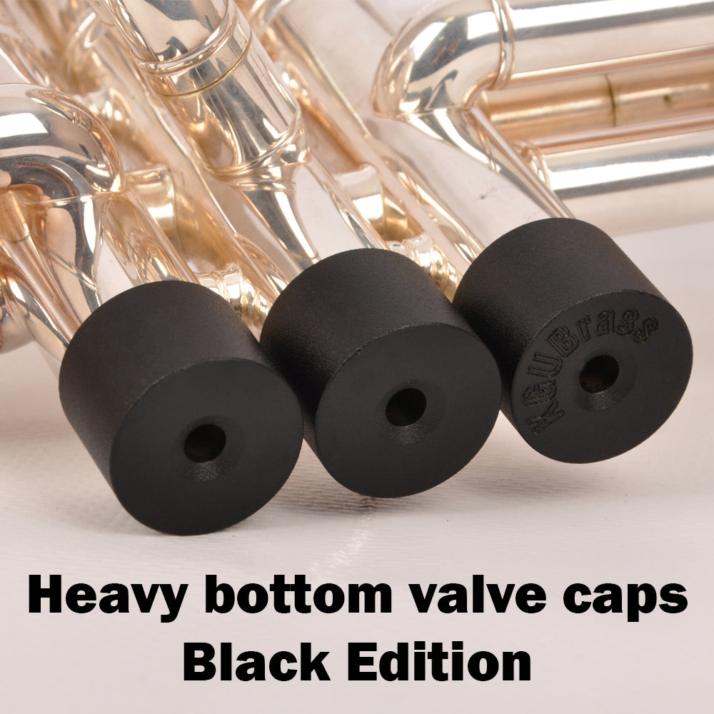 Three valve caps in black finish displayed on a trumpet.