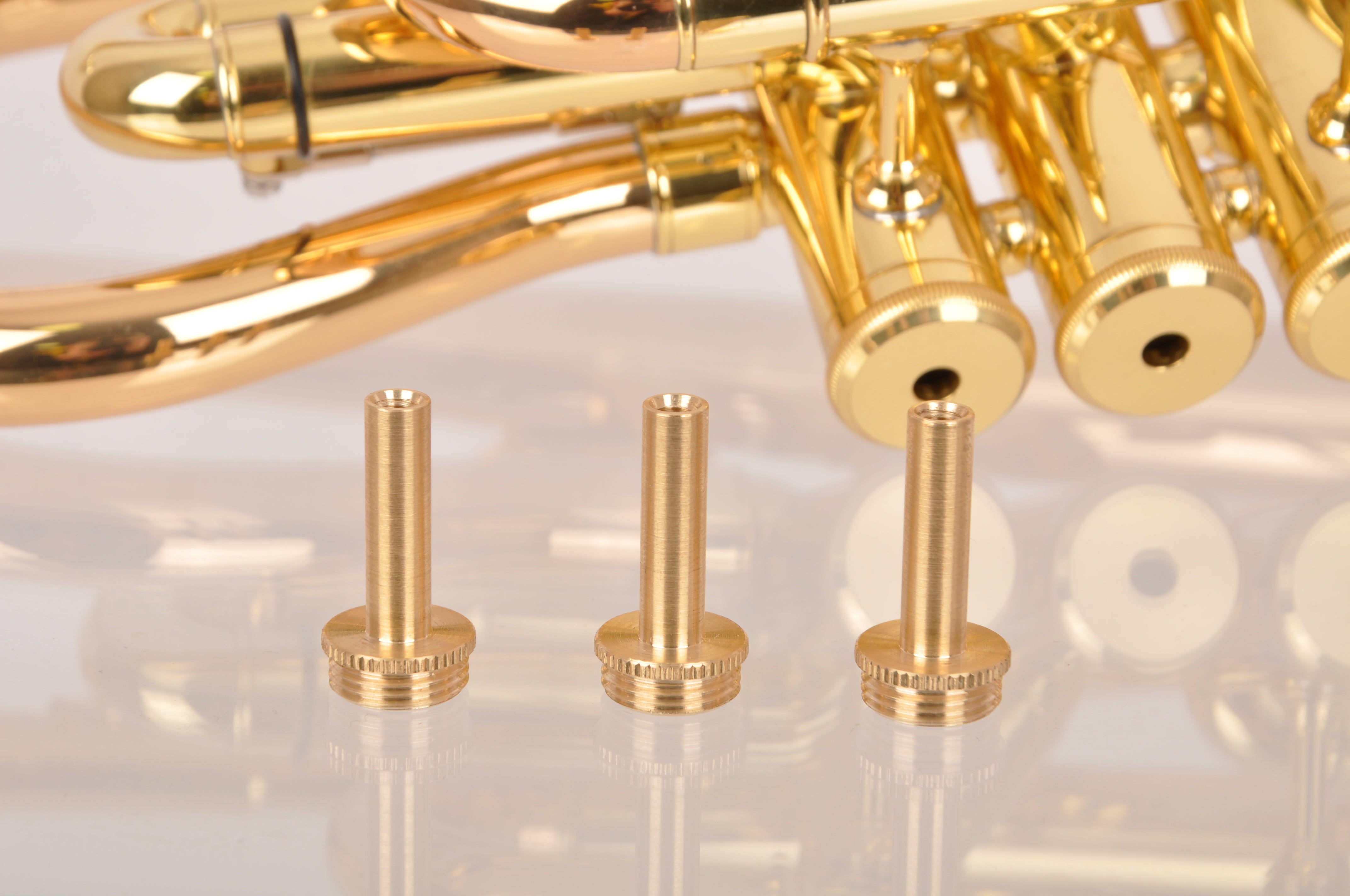 KGUmusic solid brass trumpet valve stems stand in front of the trumpet.